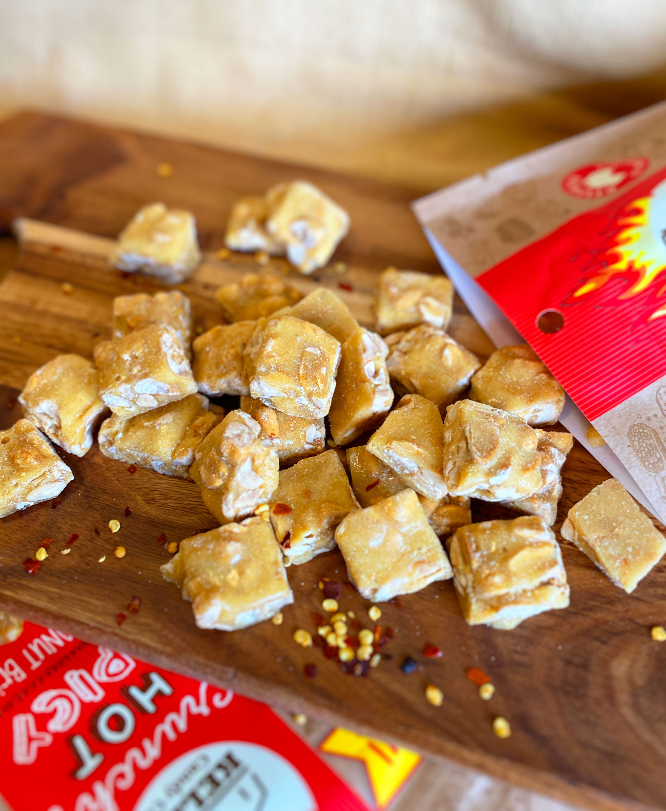 Pieces of Chilli Peanut Brittle scattered on a wooden serving platter