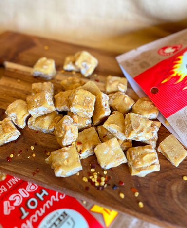 Pieces of Chilli Peanut Brittle scattered on a wooden serving platter