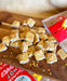 Pieces of Chilli Peanut Brittle scattered on a wooden serving platter